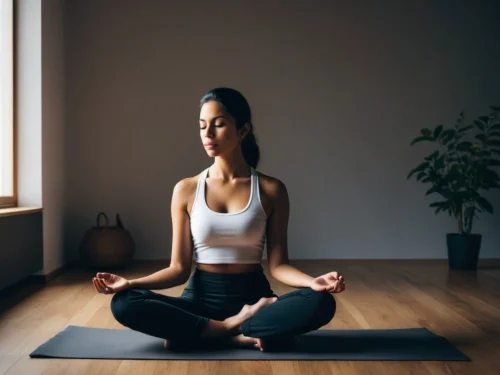 A woman sitting in meditation on the floor of her living room, in a calm and peaceful atmosphere.