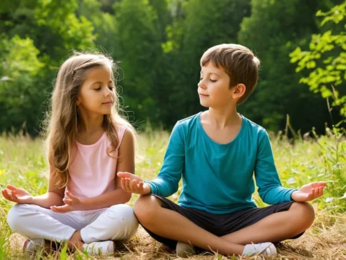 Boy and younger sister meditating together on grassy ground surrounded by lush greenery
