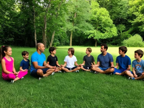 Group of children and two adults sitting in meditation pose together in green forest surrounded by natural vegetation