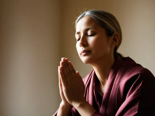 Woman praying and meditating peacefully in her home, sitting in contemplative pose