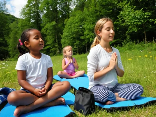 Woman leading three children in a mindfulness session while sitting together in a forest