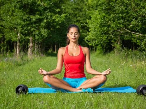 Woman in sportswear sitting on grass in meditation position, practicing mindful movement outdoors